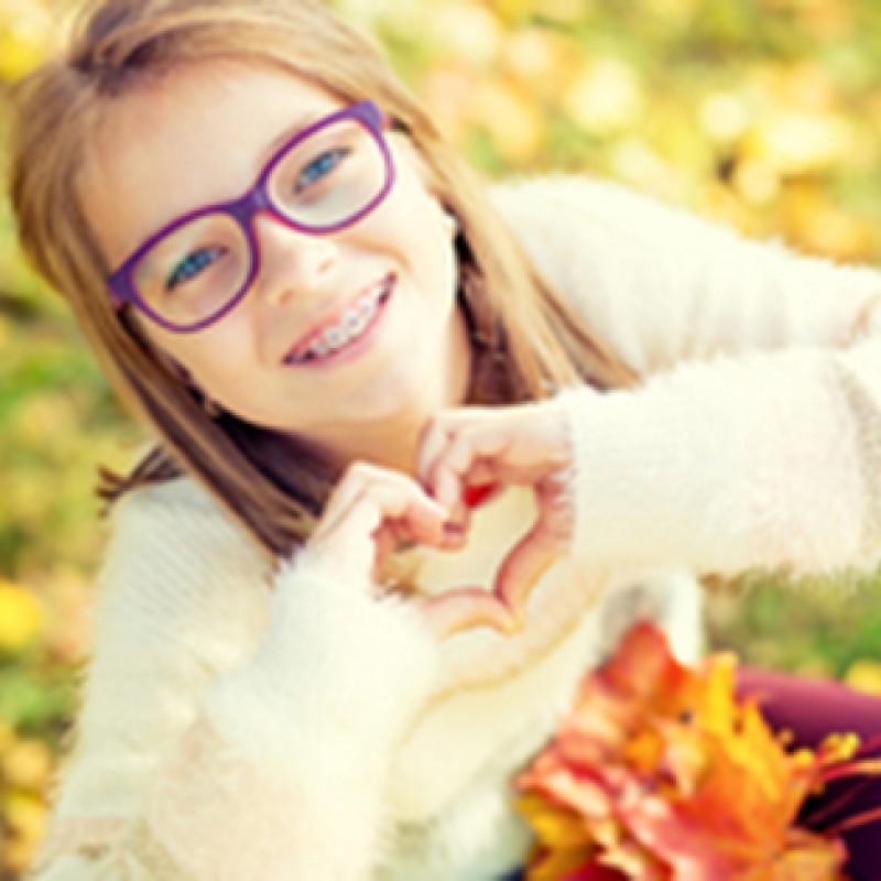 Picture of a girl with braces, smiling and making a heart with her hands