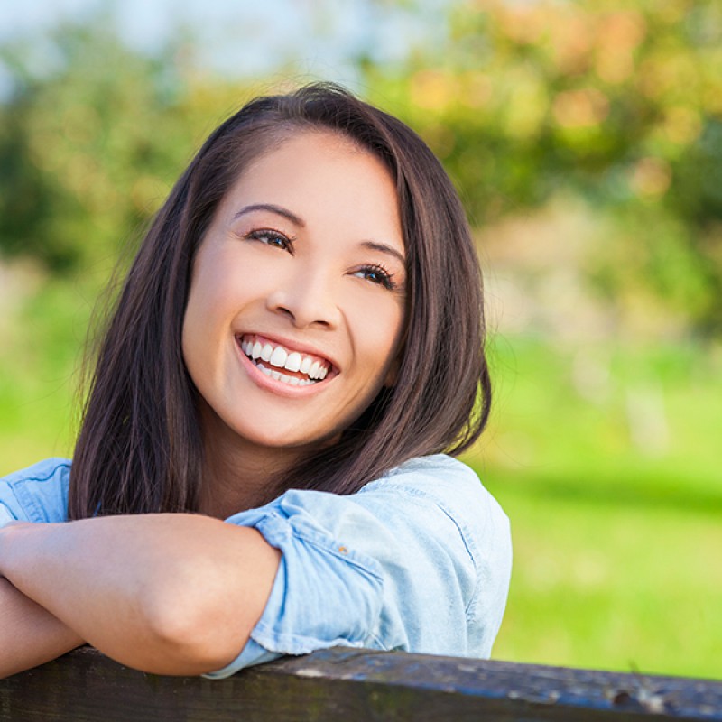 Picture of a smiling young girl with perfect teeth in a park
